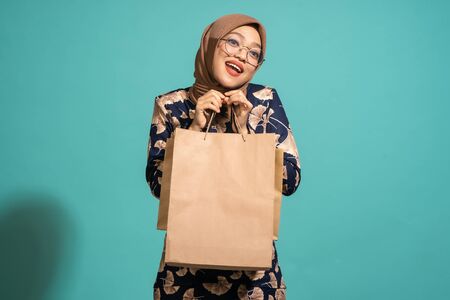 This woman is happy to be shopping. At Turquoise color backgroundの写真素材