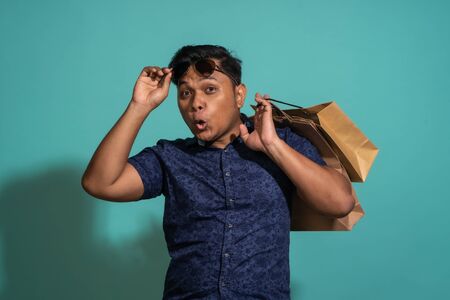 A guy who likes to shopping at turquoise background.の写真素材