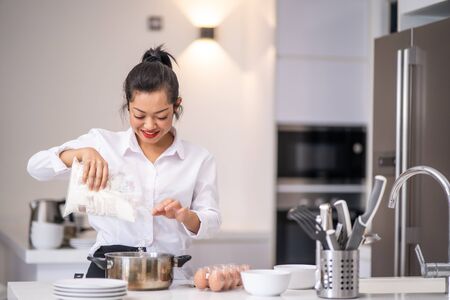 the woman was pouring flour into the bowlの写真素材