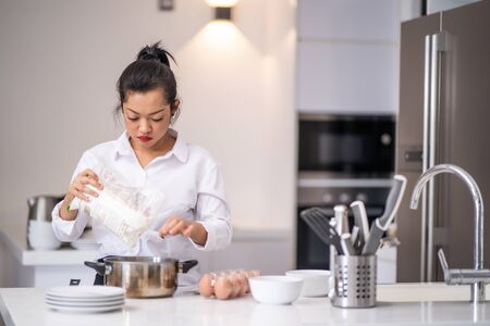 the woman was pouring flour into the bowlの写真素材