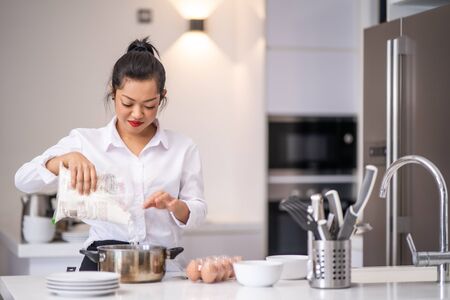 the woman was pouring flour into the bowlの写真素材