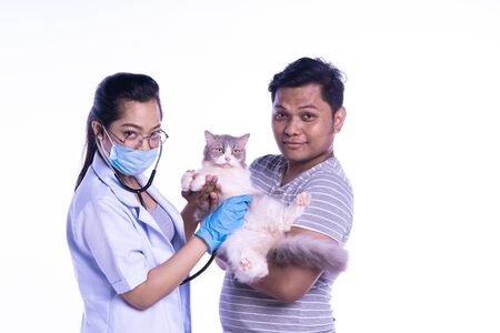 Smiling professional veterinarian holding a beautiful cat after examination, the pet owner is cuddling her cat . smiling and looking at camera.の写真素材