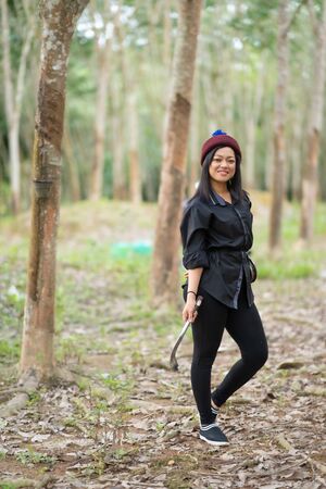 Female rubber tappers in the rubber tree row. Smiling look at the cameraの写真素材