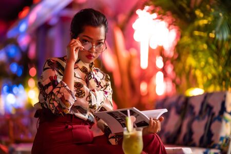 beautiful asian woman with neon light background reading bookの写真素材
