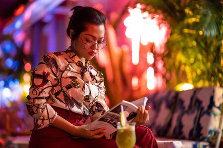 beautiful asian woman with neon light background reading bookの写真素材