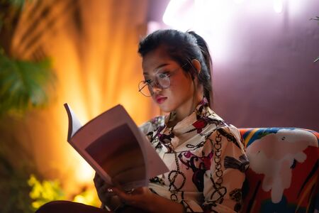 beautiful asian woman with neon light background reading bookの写真素材