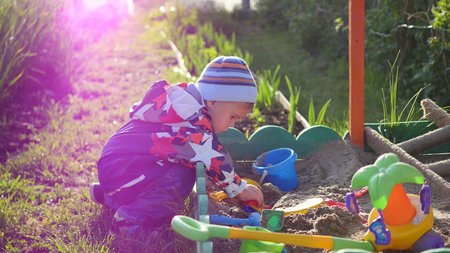 the child plays with the toys in the sandbox.Summer Sunny day. Fun and games outdoors
