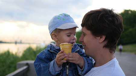 the child and the father is eating in a waffle Cup ice cream closeup. Family festival in the Park