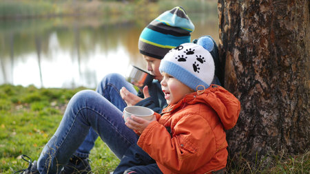 in the autumn Park children sitting on the lawn and drink hot tea, walk in the fresh airの写真素材