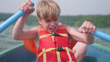 The guy floats on the boat. Teen independently operates a boat with the help of oars. Extreme sport