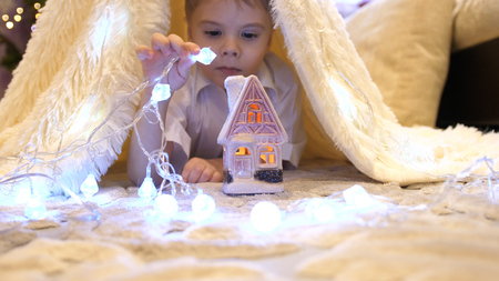 The child plays in the childrens room in a tent with a Christmas light. Happy childhoodの写真素材