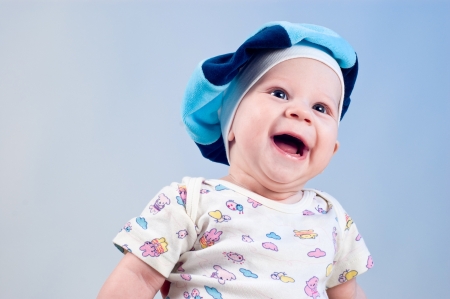Amusing baby boy in a beret in a studio on a dark blue backgroundの写真素材
