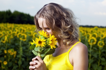 Sun young girl in the field with sunflowersの写真素材