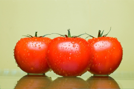 Three juicy tomatoes on a yellow backgroundの写真素材