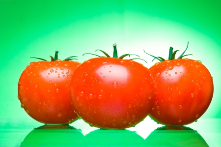 Three juicy tomatoes on a green backgroundの写真素材