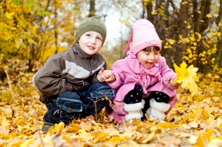 Little boy and girl play in a park in autumnの写真素材