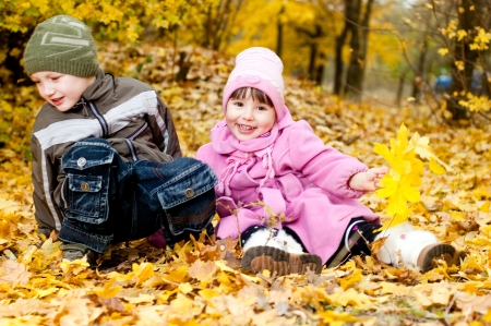 Little boy and girl play in a park in autumnの写真素材