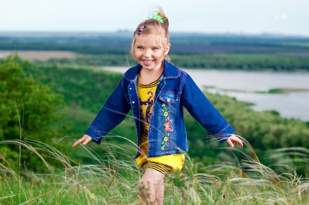 Beautiful little girl in jean clothes on a walk outdoorsの写真素材