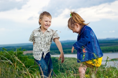 A little girl and boy play and cheered on a walk outdoorsの写真素材