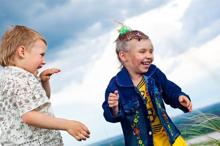 A little girl and boy play and cheered on a walk outdoorsの写真素材