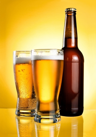 Two glasses and Bottle of fresh light beer on yellow backgroundの写真素材