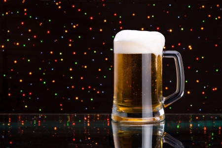Mug fresh beer with cap of foam on colored light backgroundの写真素材