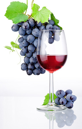 Glass of red wine and bunch of grapes with leaves isolated on a white backgroundの写真素材