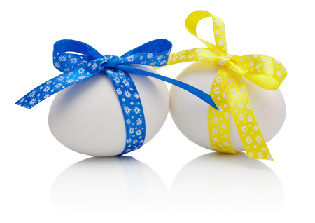 Two Easter eggs with festive blue and yellow bow isolated on white backgroundの写真素材
