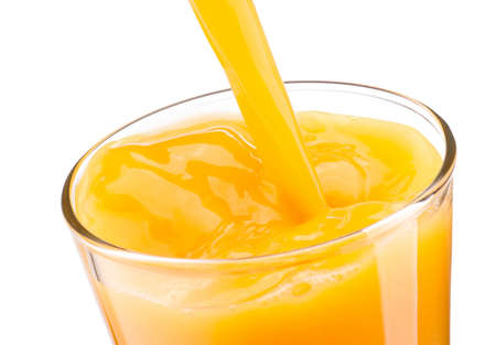 Orange juice pouring into glass isolated on a white backgroundの写真素材