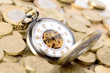 Concept of time is money, old watch on a pile of coinsの写真素材