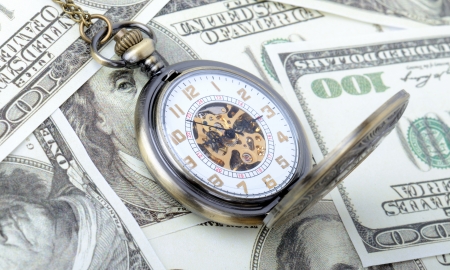 Concept of time is money, old watch on a pile dollar notesの写真素材