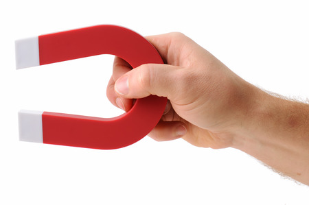 A hand holding a magnet isolated on white to pick up an objectの写真素材