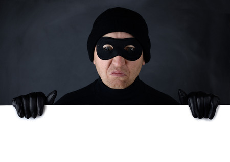 Thief peering over the top of isolated white copy spaceの写真素材