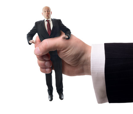 Businessman being squashed in a hand isolaed on a white background, concept of problems at work.の写真素材