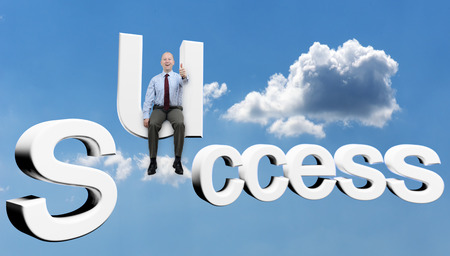 Businessman sat on text of success in the skyの写真素材