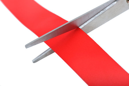Closeup image of scissors cutting a red ribbon.の写真素材