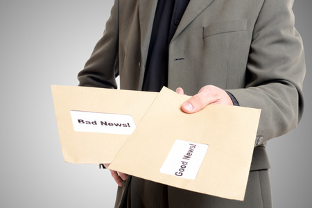 man in suit showing two envelopes one with good news and one with badの写真素材