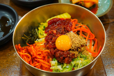Colorful Ingredients of Jeonju Bibimbap with Raw Beef and Egg Yolk in a Traditional Korean Brass Bowlの写真素材