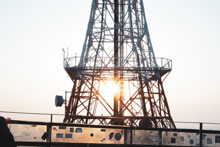 Communication Tower and Graffiti Railing Covered with Love Locks Under the Sunset Glowの写真素材
