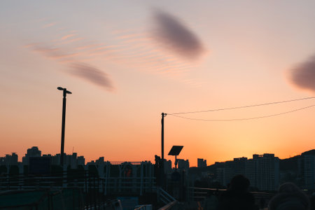 City Rooftop View of Building Silhouettes Against an Orange Sunset Skyの写真素材