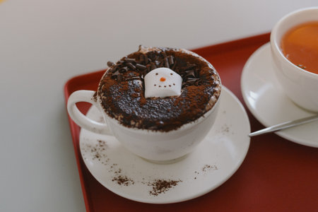 Cozy Cafe Table with a Mug of Hot Chocolate Topped with a Snowman Decorationの写真素材