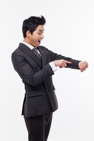 Young business man consulting his watch, isolated over whiteの写真素材