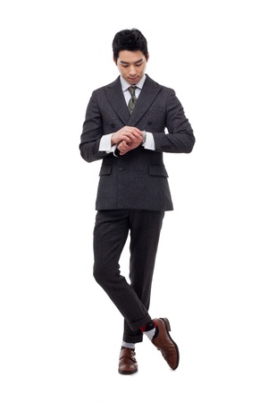 Young business man consulting his watch, isolated over whiteの写真素材