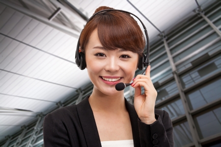 Smiling call center operator asian business woman in business background. の写真素材