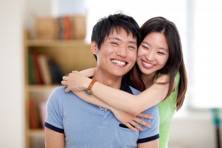 Happy young Asian couple isolated in home background.の写真素材