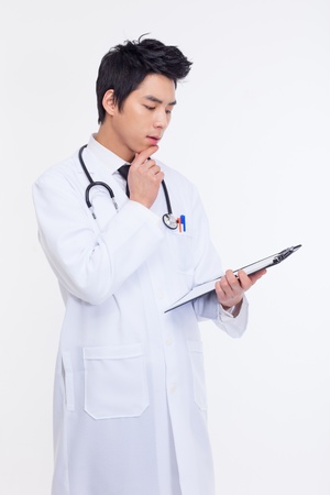 Thinking young Asian doctor isolated on white backgroundの写真素材