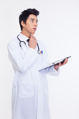 Thinking young Asian doctor isolated on white backgroundの写真素材