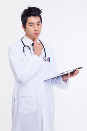 Thinking young Asian doctor isolated on white backgroundの写真素材