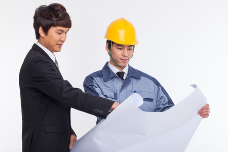 Asian business man and engineer having a blueprint isolated on white.の写真素材