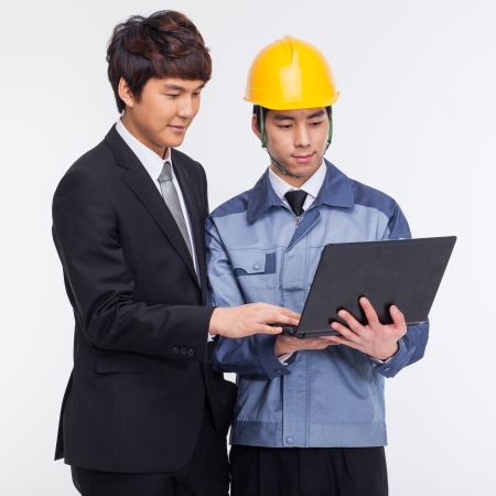 Business man and engineer looking laptop isolated on whiteの写真素材